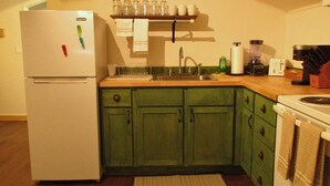 A kitchen with a white refrigerator, green cabinets, a wooden countertop, a sink, and various appliances including a blender and a coffee maker. - The Loft at Aspen Pine with Wi-Fi, AC in wonderful Hot Springs (Hot Springs)