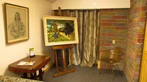 A room with a wooden table, a framed painting, a clear plastic chair, and a brick wall. - The Loft at Aspen Pine with Wi-Fi, AC in wonderful Hot Springs (Hot Springs)
