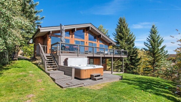 Een modern huis met twee verdiepingen, een jacuzzi, terras en grote ramen.