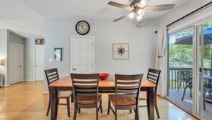 A dining area with a wooden table, four chairs, a ceiling fan, a clock, and a door. - Charming Cottage with Wifi, Screened Porch Just Feet From the Lake (Moneta)