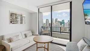 Un salon moderne avec un canapé, une table ronde et une grande fenêtre donnant sur la ville.