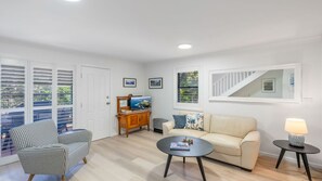 Un salon comprenant un canapé, deux fauteuils, une table basse, un téléviseur et une lampe.