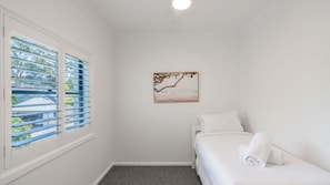 Une chambre d’hôtel avec un lit, une fenêtre avec des stores et un tableau accroché au mur.