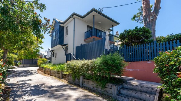 A two-story residential building with a balcony, a red wall, and a blue fence.
