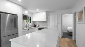 A modern kitchen with white cabinetry, a stainless steel refrigerator, and a central island.