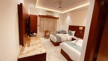 A hotel room with two beds, a marble countertop, a wooden headboard, a ceiling fan, and an air conditioning unit.