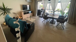 Uma sala de estar moderna com sofá, televisão, mesa de jantar e cadeiras.