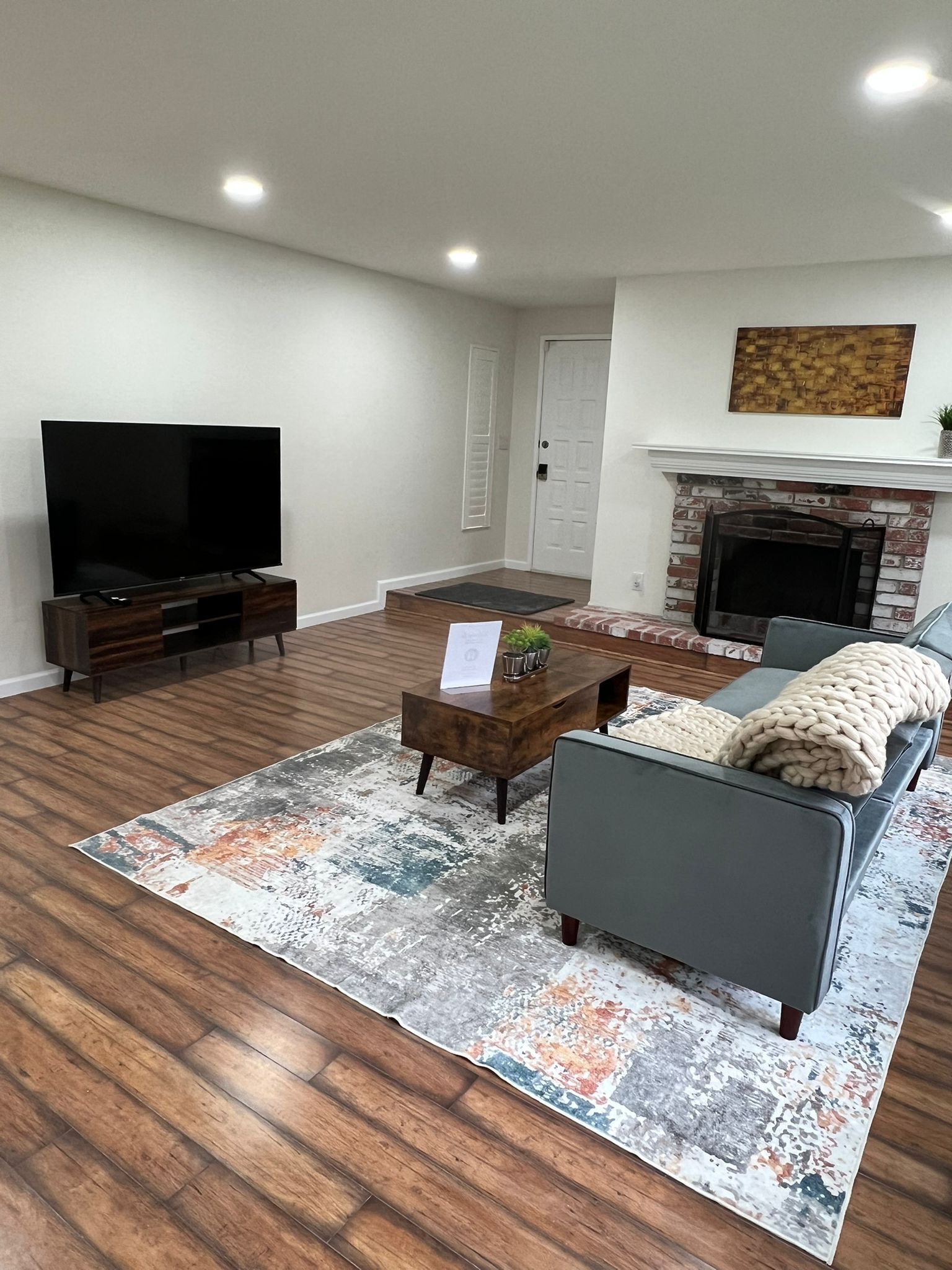 Una sala de estar con televisión de pantalla plana, un sofá, una mesa de centro y una chimenea.