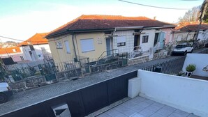 Una terraza en la azotea con suelo de baldosas, una escalera de metal y vistas a casas vecinas.
