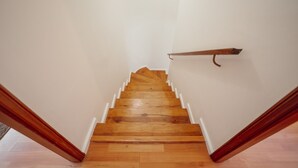 Una escalera de madera con paredes blancas y barandilla.