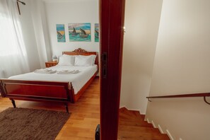 Ein Schlafzimmer mit einem hölzernen Bett, weißen Leinen, einem flauschigen Teppich und zwei Bildern an der Wand.