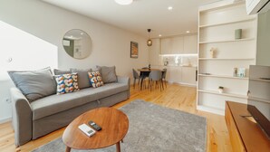 A modern living room with a grey sofa, a wooden coffee table, and a dining area with a table and chairs. - Gaia Premium B Apartment by Vacationy (Vila Nova de Gaia)