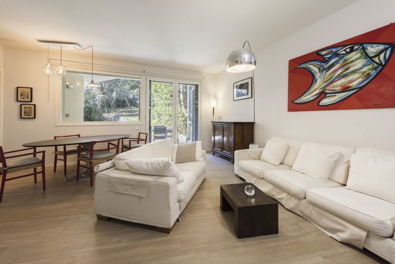 Un salon moderne avec un canapé blanc, une table à manger avec des chaises, une table basse et une cheminée.