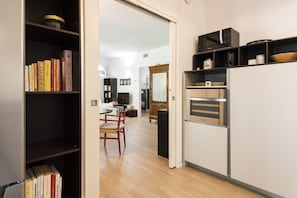 Une cuisine compacte équipée d’un four à micro-ondes, d’un four traditionnel et d’un coin repas avec une chaise et une table.