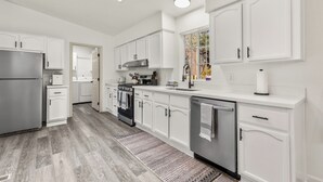A modern kitchen with white cabinetry, stainless steel appliances, and a patterned rug.