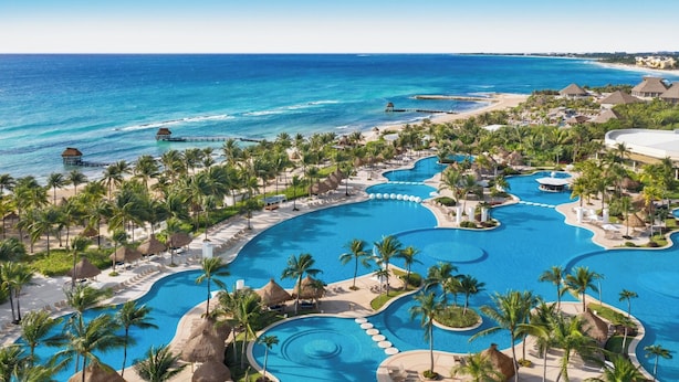 A resort with multiple swimming pools, palm trees, and a beach.