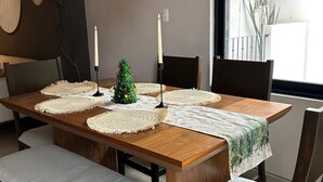A dining area with a wooden table, white placemats, candles, and a small Christmas tree. - Taxqueño Charm  (Taxco de Alarcón)