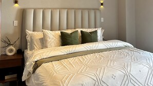 A bedroom with a wooden ceiling, a bed with white bedding and green pillows, and two wall-mounted lights. - Taxqueño Charm  (Taxco de Alarcón)