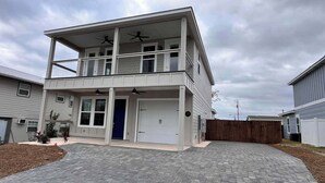 Ein zweistöckiges Haus mit überdachter Veranda, Garage und gepflasterter Auffahrt.