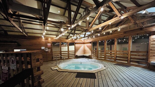A wooden cabin interior with a hot tub, wooden walls, and a sloped ceiling. - A Perfect Mountain Getaway with Hot Tubs, and steps to Soaring Eagle ski lift! (Snowshoe)