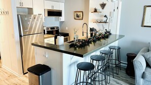 A modern kitchen with a central island, stainless steel appliances, and bar stools. - A Perfect Mountain Getaway with Hot Tubs, and steps to Soaring Eagle ski lift! (Snowshoe)