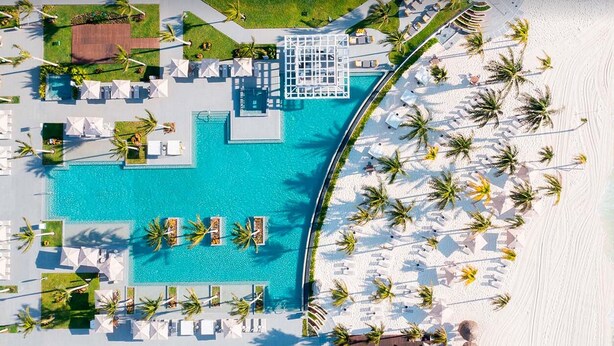 An aerial view of a resort with a large pool, beach area, and palm trees. - garza blanca cancun (Punta Sam)