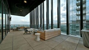 A spacious balcony with a sofa, chairs, and a small table. - Rainey St LuxuryCondo w/ Balcony (Austin)
