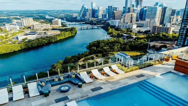 A rooftop pool with lounge chairs and a city skyline in the background. - Rainey St LuxuryCondo w/ Balcony (Austin)