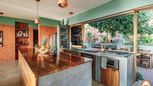 Een moderne keuken met een groot eiland, inbouwapparatuur en uitzicht op de tuin.
