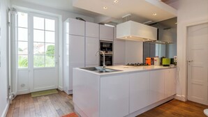 Una cucina moderna con isola centrale, mobili bianchi e un'ampia finestra.
