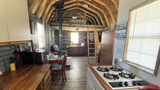 A rustic kitchen with wooden beams, a central island, and a stove. - Terrific 1-bedroom off grid cabin in Belfry with Mountain View (Belfry)