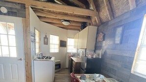 A rustic kitchen with wooden beams, a dining table with chairs, and a refrigerator. - Terrific 1-bedroom off grid cabin in Belfry with Mountain View (Belfry)