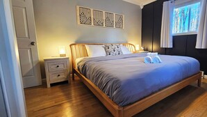 Un lit bien fait, avec une couverture bleue et des serviettes pliées, une table de chevet avec une lampe et une fenêtre avec des rideaux.