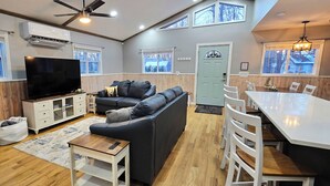 Un salon moderne avec un canapé, un téléviseur et un coin repas.