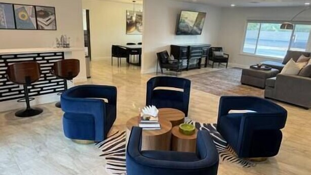 Una sala moderna con chimenea, sillones azules, una mesa de centro y un comedor con televisor.