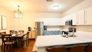 A modern kitchen with white cabinets, stainless steel appliances, and a central island with bar stools.