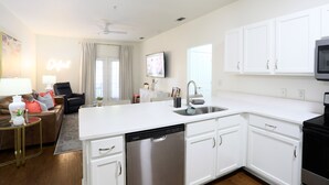 Une cuisine moderne avec des meubles blancs, un lave-vaisselle et une cuisinière noire.