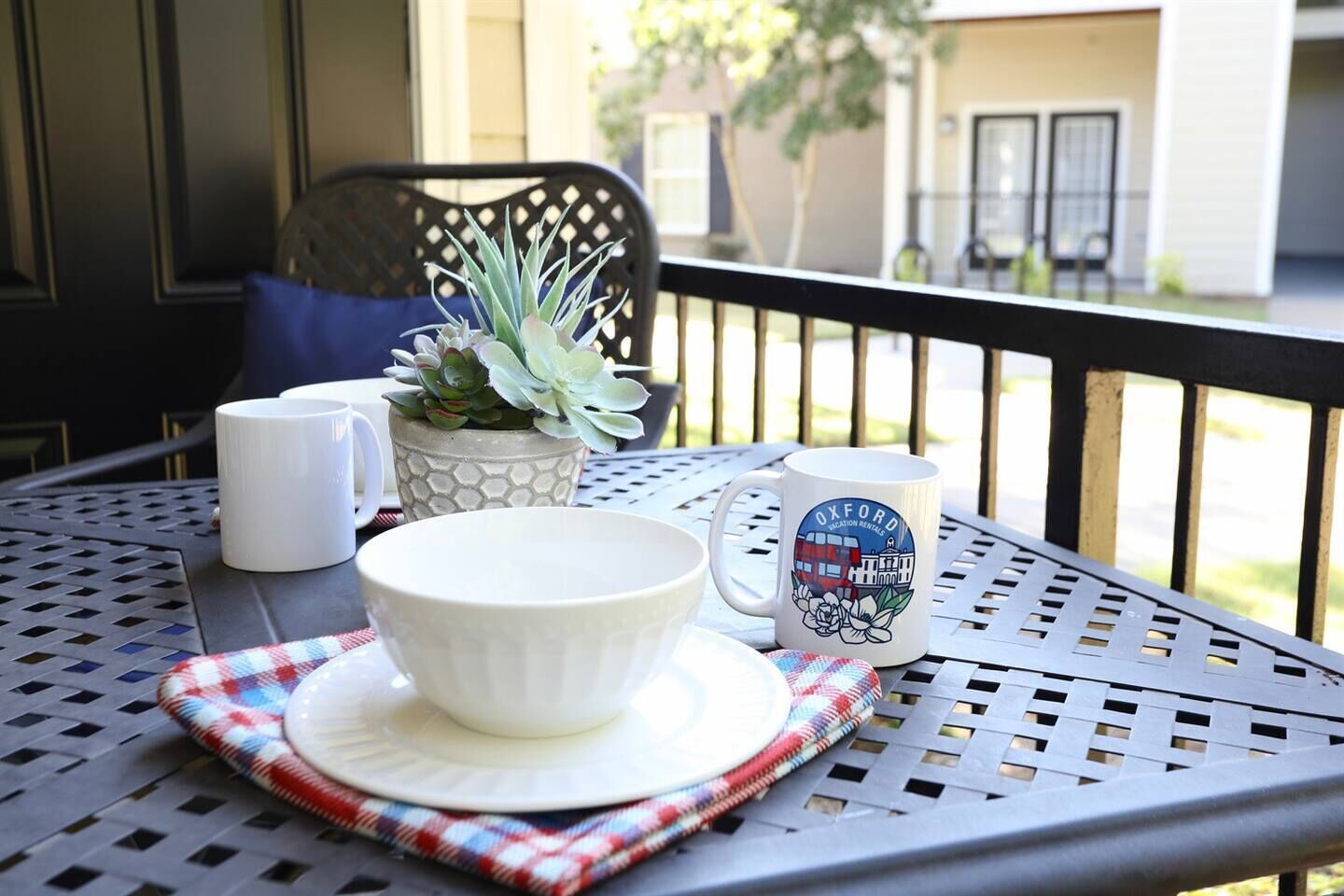 Ein Tisch mit einer weißen Schüssel, einer weißen Tasse und einer Tasse mit einer Gebäudeansicht.