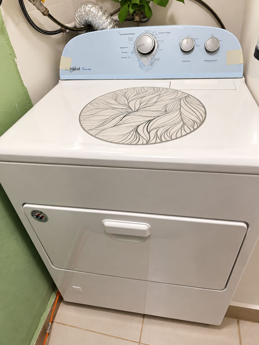 A white washing machine with a leaf pattern on the top, a control panel with knobs, and a front handle.