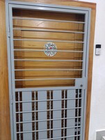 Una reja metálica con un panel de madera y una pegatina con texto.