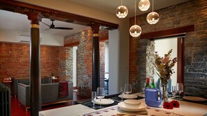 A dining area with a brick wall, a table set for four, and hanging spherical lights. - The Madder Suite at Blue Violin (Belleville)