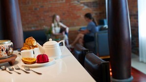 Un desayuno con croissants, un pastel de terciopelo rojo y una tetera sobre una mesa.