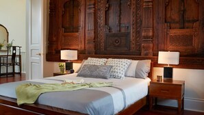 Un dormitorio con una cama grande, dos mesitas de noche y un cabecero de madera con intrincados grabados.