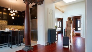 Una cocina moderna con armarios oscuros, una columna central e iluminación colgante.