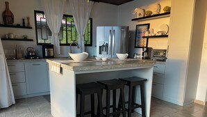 Una cocina moderna con una isla central, taburetes de bar y un refrigerador grande.