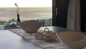 Una mesa de comedor con varios cuencos y un jarrón, en un balcón con vistas panorámicas.