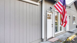 A building with a gray exterior and a white door. An American flag is displayed outside. - Electric Fireplace: Central Coeur d'Alene Studio! (Coeur d'Alene)