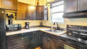 A kitchen with dark wooden cabinets, a microwave, a stove, and a sink. - Electric Fireplace: Central Coeur d'Alene Studio! (Coeur d'Alene)