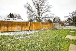 Enjoy a serene outdoor space with a grassy lawn and a wooden fence, surrounded by trees and a charming building.