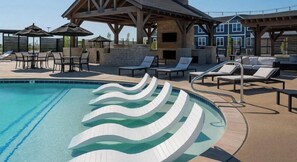 Une piscine avec des marches blanches ondulées, des chaises longues et un espace de détente abrité.